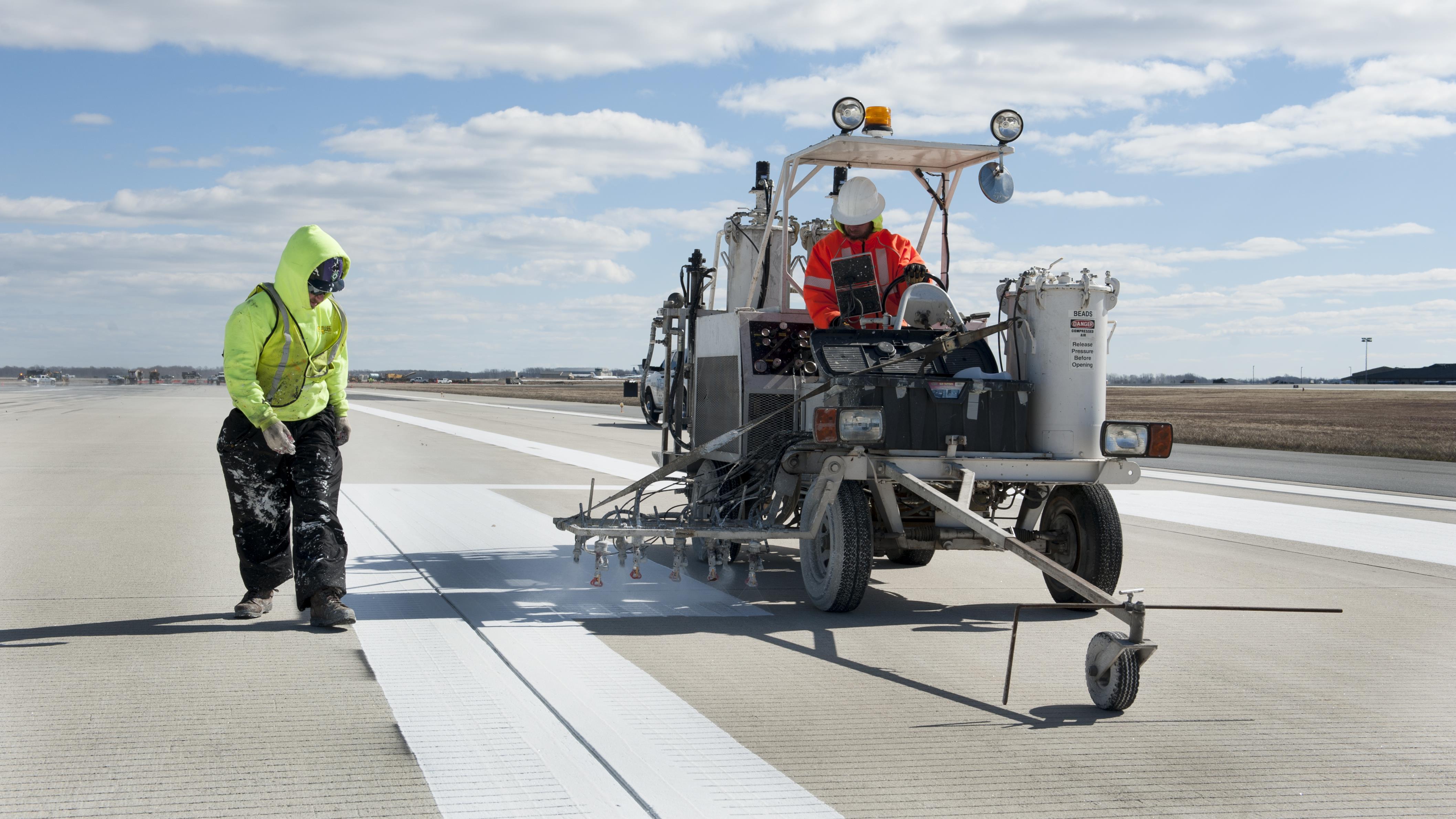 Two Airmen repainting a runway